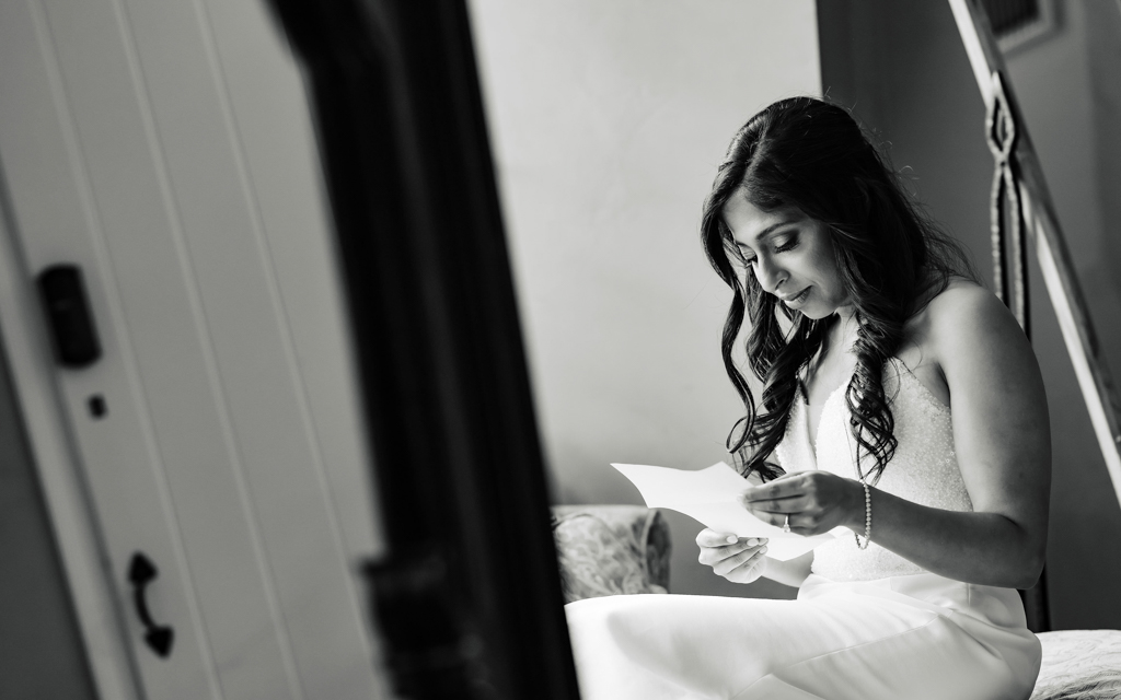 Bride reads a heartfelt letter on her wedding day in the Pleasantdale Chateau bridal suite.